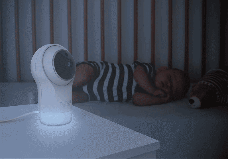 Glowing baby monitor beside a sleeping baby at night